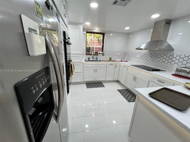 kitchen with stainless steel fridge, tasteful backsplash, wall chimney exhaust hood, sink, and white cabinetry