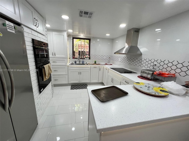 kitchen with black appliances, wall chimney range hood, sink, decorative backsplash, and white cabinetry