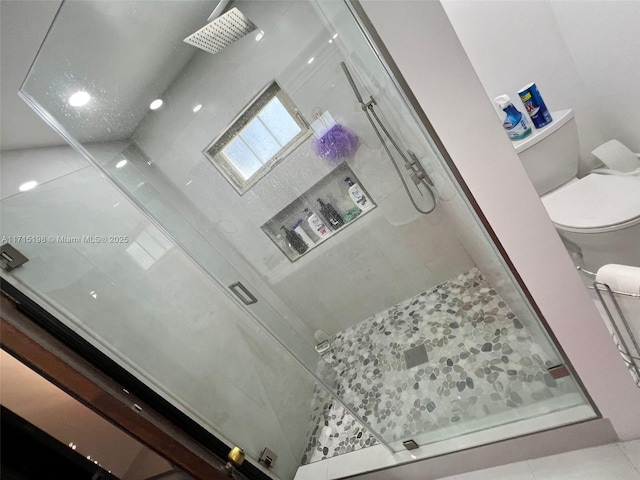 bathroom featuring tile patterned floors, toilet, and walk in shower