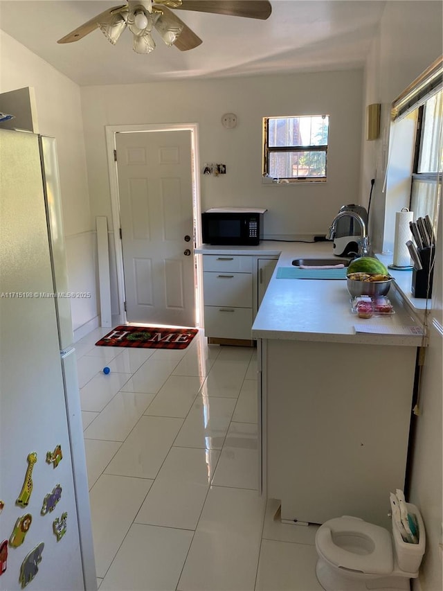 kitchen featuring ceiling fan, sink, white refrigerator, kitchen peninsula, and light tile patterned flooring