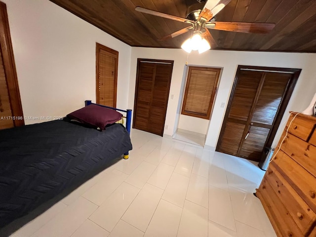 bedroom featuring ceiling fan, multiple closets, and wood ceiling