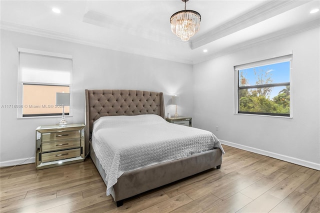 bedroom featuring a chandelier, light wood-type flooring, a tray ceiling, and crown molding