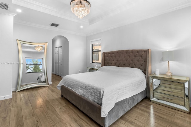 bedroom featuring a chandelier, wood-type flooring, a closet, and crown molding