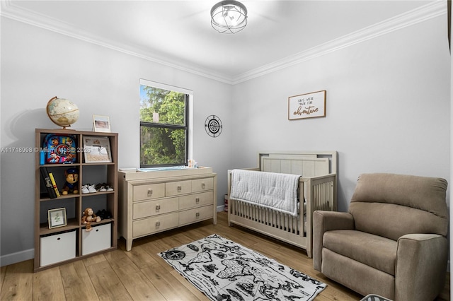 bedroom with light wood-type flooring, crown molding, and a nursery area