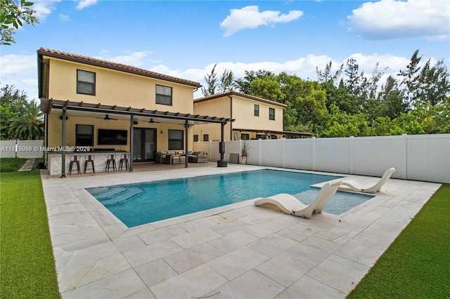 view of pool with ceiling fan, a patio area, a bar, and exterior kitchen