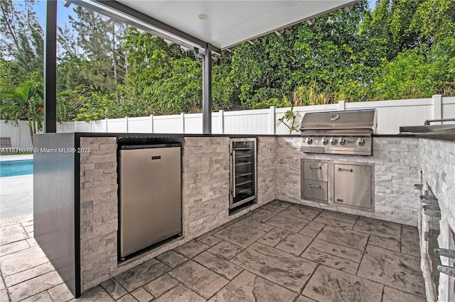 view of patio with wine cooler, a fenced in pool, and area for grilling