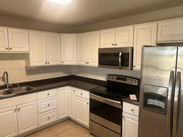 kitchen with a sink, stainless steel appliances, white cabinets, and light tile patterned floors