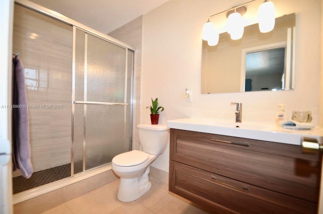 bathroom featuring tile patterned flooring, vanity, a shower with shower door, and toilet