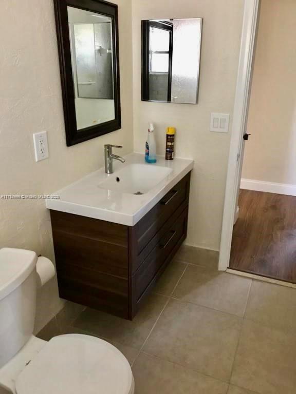 bathroom with tile patterned floors, baseboards, toilet, and vanity