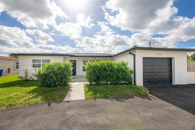 single story home featuring a garage and a front lawn