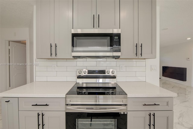 kitchen with stainless steel appliances, light stone counters, and tasteful backsplash