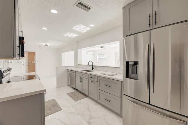 kitchen with gray cabinets, sink, a textured ceiling, and appliances with stainless steel finishes