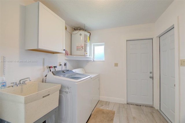 clothes washing area with cabinets, light wood-type flooring, electric water heater, sink, and independent washer and dryer