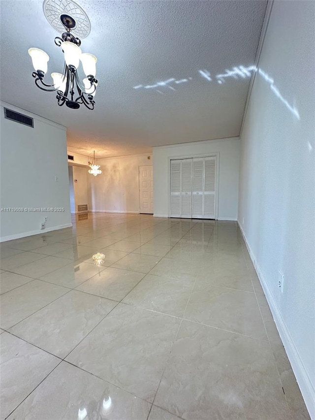 unfurnished room with a chandelier and a textured ceiling