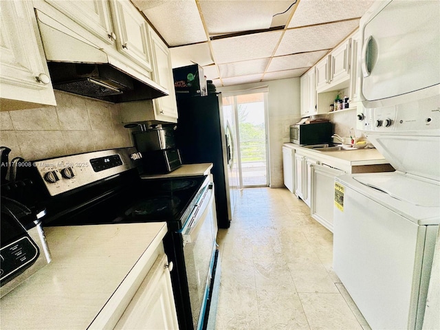 kitchen with a paneled ceiling, sink, stacked washer and dryer, electric range, and tasteful backsplash