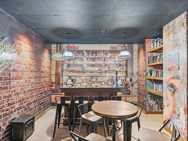 dining space with bar area, a paneled ceiling, and brick wall