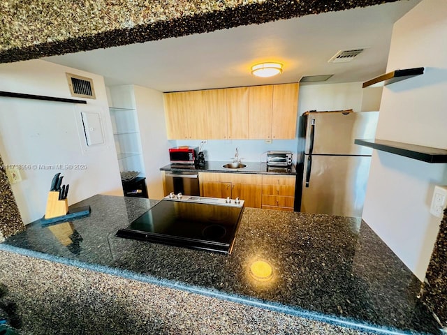 kitchen with dark stone countertops and stainless steel fridge