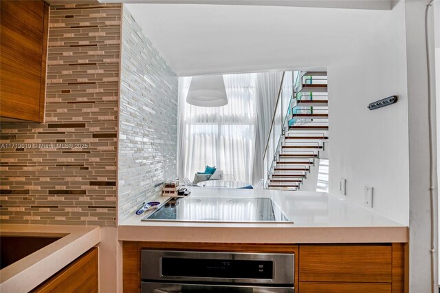 kitchen featuring black electric cooktop, backsplash, and oven