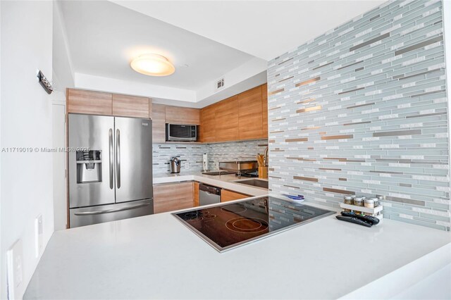 kitchen featuring appliances with stainless steel finishes, kitchen peninsula, and decorative backsplash