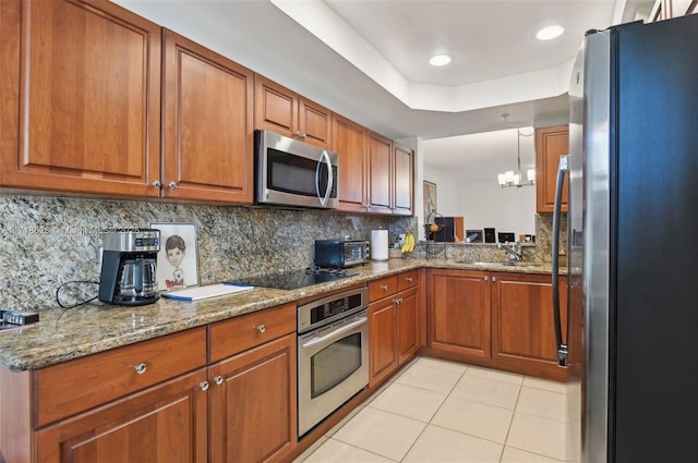 kitchen with appliances with stainless steel finishes, a chandelier, light tile patterned floors, decorative backsplash, and sink