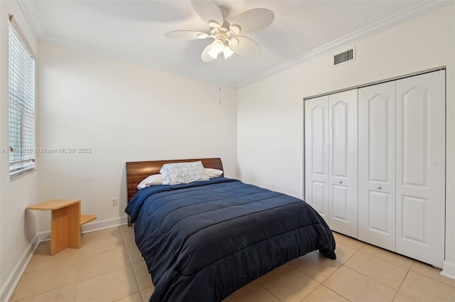 bedroom with a closet, light tile patterned floors, ceiling fan, and ornamental molding