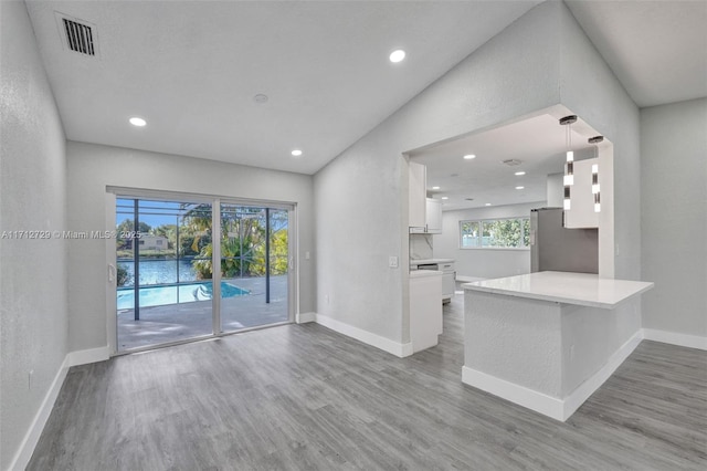 kitchen featuring kitchen peninsula, stainless steel fridge, white cabinets, and light hardwood / wood-style floors