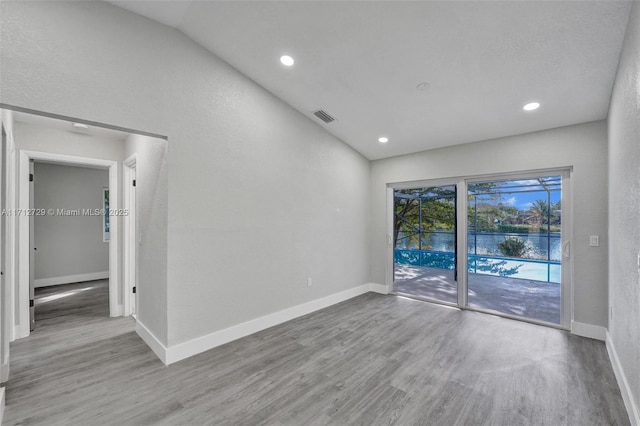 unfurnished room with light wood-type flooring and vaulted ceiling