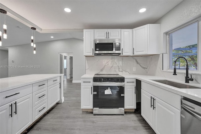 kitchen with sink, appliances with stainless steel finishes, pendant lighting, white cabinets, and light wood-type flooring