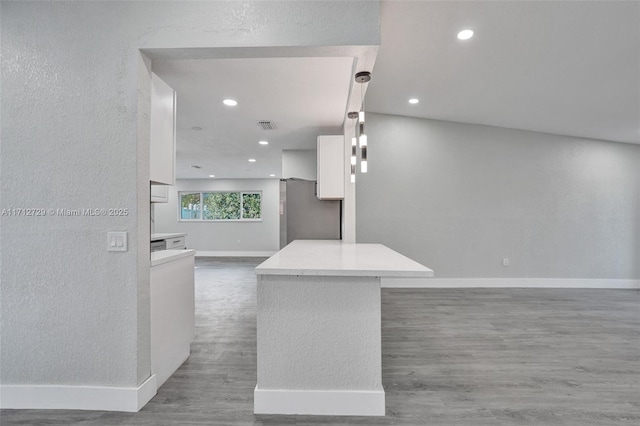 interior space with white cabinets, pendant lighting, hardwood / wood-style flooring, and stainless steel refrigerator