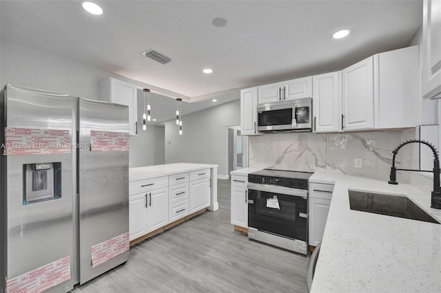 kitchen with sink, stainless steel appliances, pendant lighting, decorative backsplash, and white cabinets