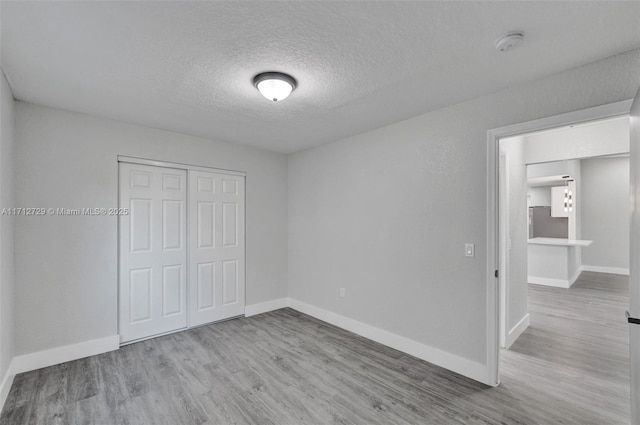 unfurnished bedroom with a closet, a textured ceiling, and light hardwood / wood-style flooring