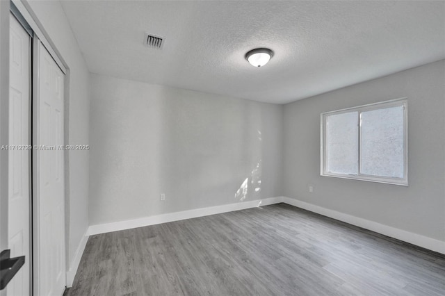 unfurnished room with hardwood / wood-style flooring and a textured ceiling