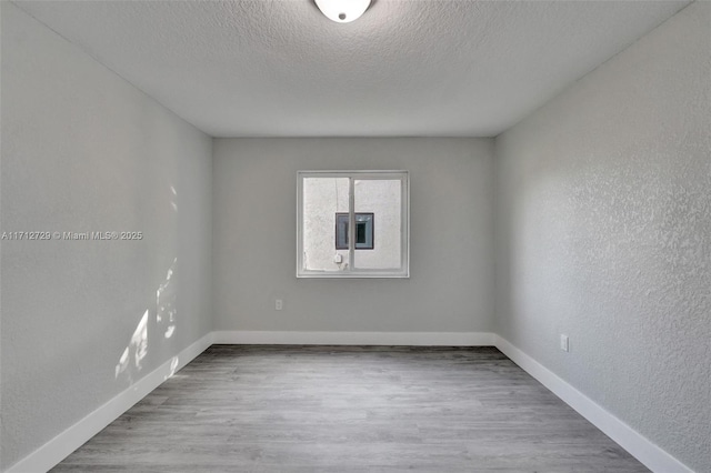 spare room featuring light hardwood / wood-style floors and a textured ceiling