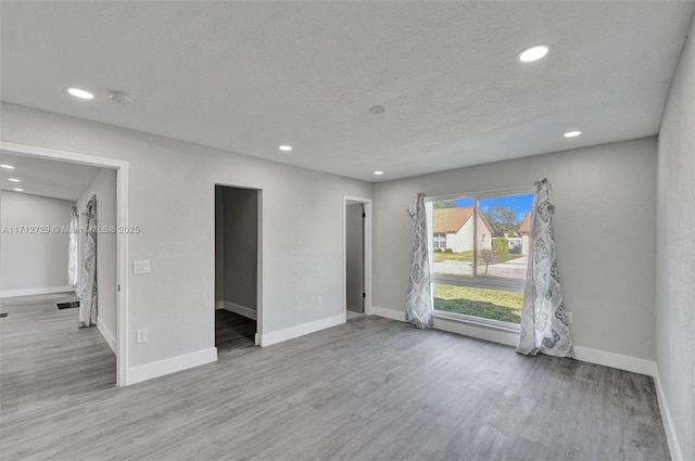 spare room with a textured ceiling and light hardwood / wood-style floors