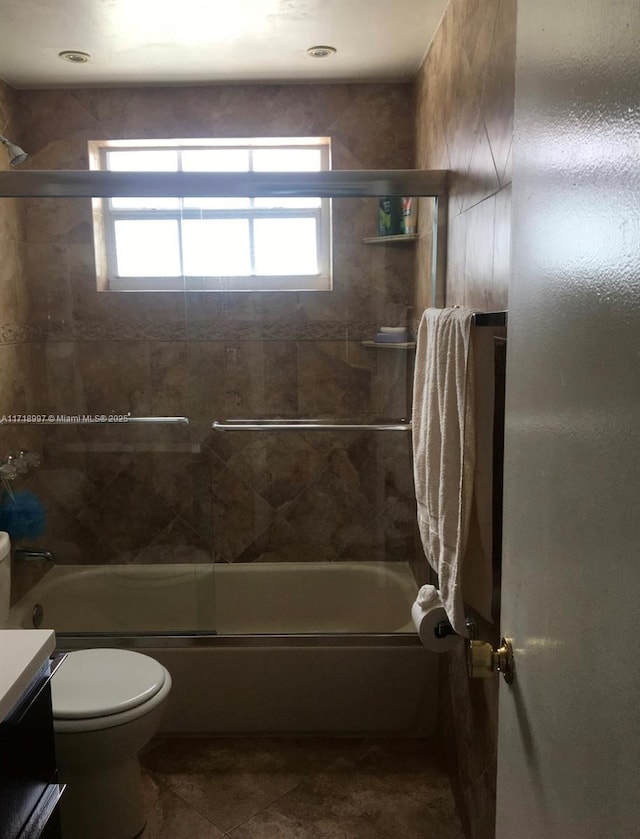 full bathroom with vanity, a healthy amount of sunlight, toilet, and bath / shower combo with glass door