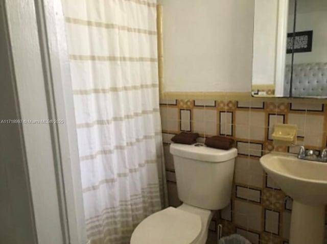 bathroom featuring tile walls and toilet