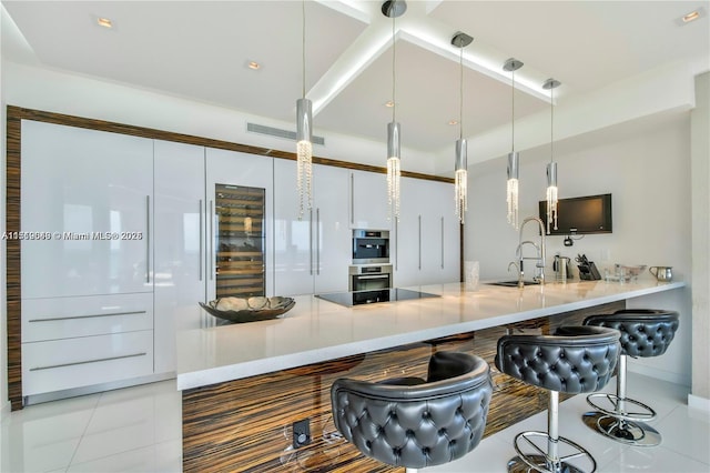 kitchen with kitchen peninsula, light tile patterned floors, hanging light fixtures, and sink