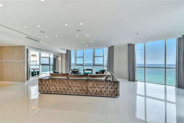 tiled living room with expansive windows and a water view