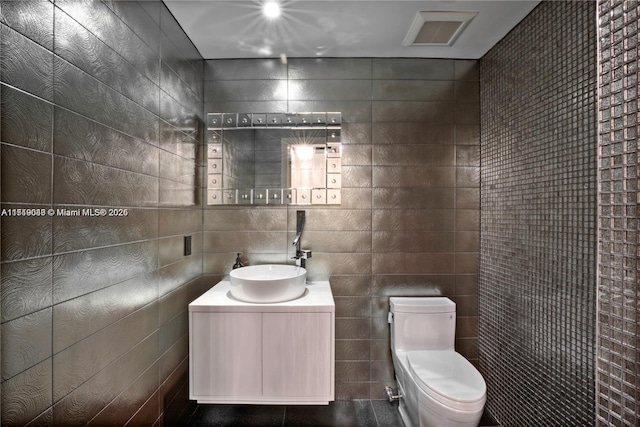 bathroom with vanity, toilet, and tile walls