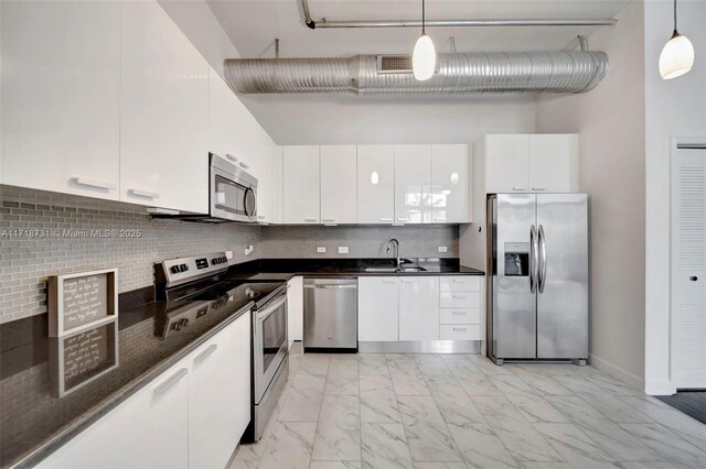 kitchen featuring pendant lighting, a wall of windows, appliances with stainless steel finishes, white cabinetry, and decorative backsplash