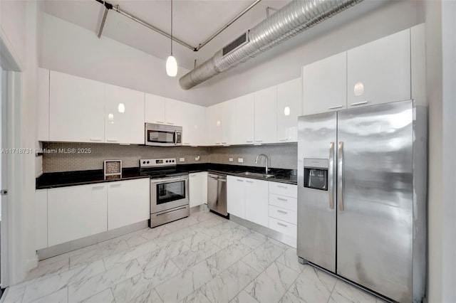 kitchen with sink, hanging light fixtures, white cabinets, stainless steel appliances, and backsplash