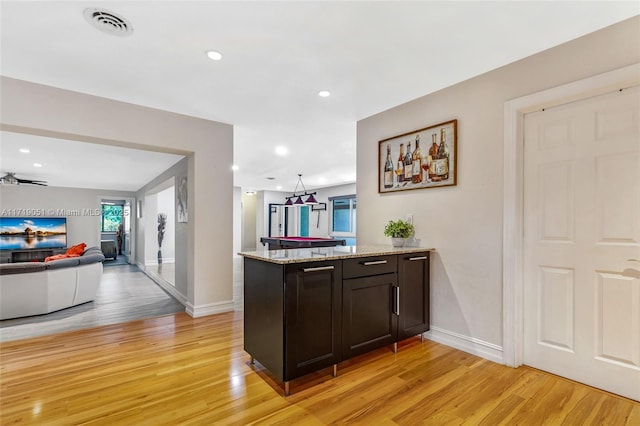 kitchen featuring kitchen peninsula, light hardwood / wood-style floors, and light stone counters