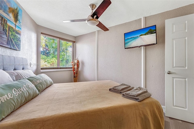 bedroom with hardwood / wood-style floors, ceiling fan, and a textured ceiling