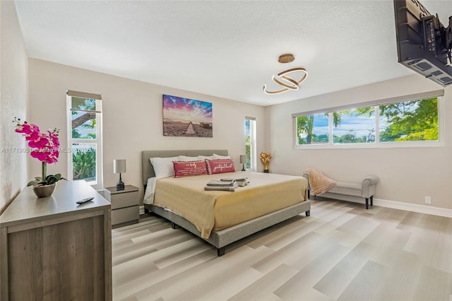 bedroom featuring light hardwood / wood-style floors and a textured ceiling