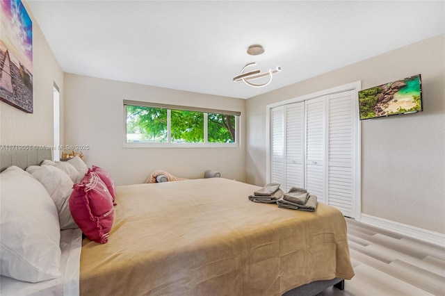 bedroom with light hardwood / wood-style floors and a closet