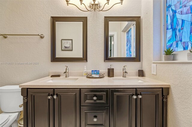 bathroom featuring vanity, a notable chandelier, and toilet