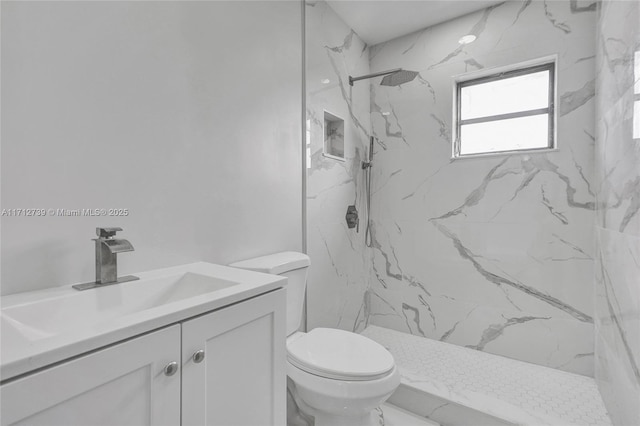 bathroom with a tile shower, vanity, and toilet