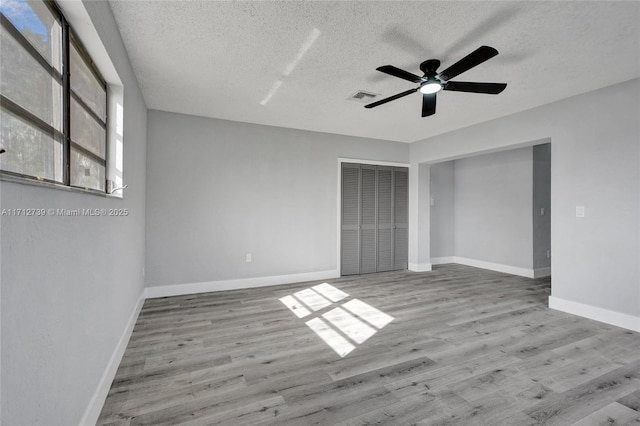 unfurnished bedroom featuring a textured ceiling, a closet, ceiling fan, and light hardwood / wood-style floors