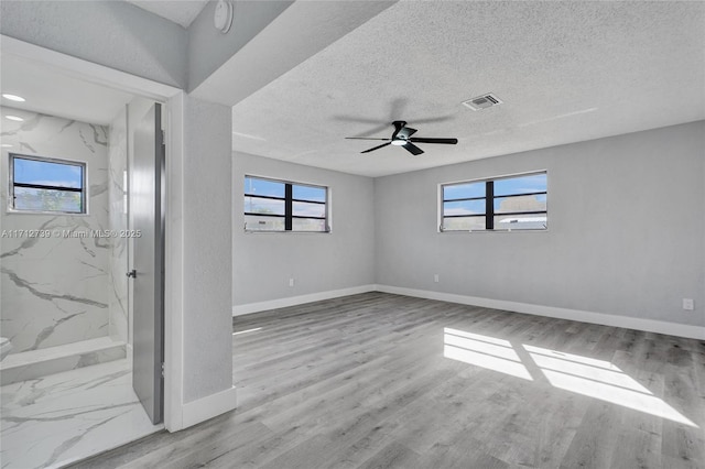 unfurnished room with ceiling fan, a textured ceiling, and a wealth of natural light