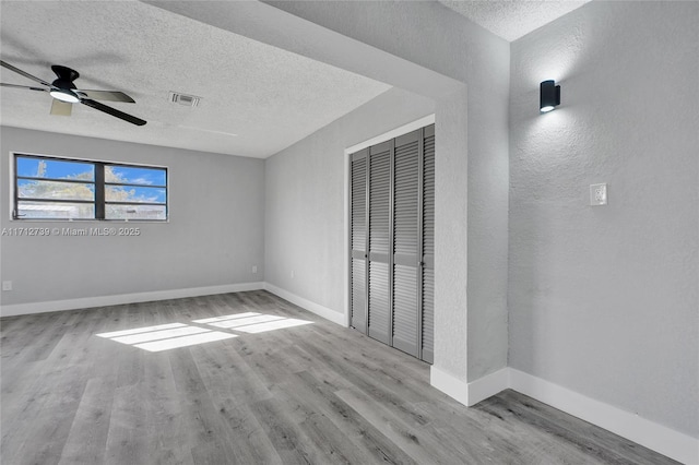 unfurnished bedroom with ceiling fan, light hardwood / wood-style floors, a textured ceiling, and a closet